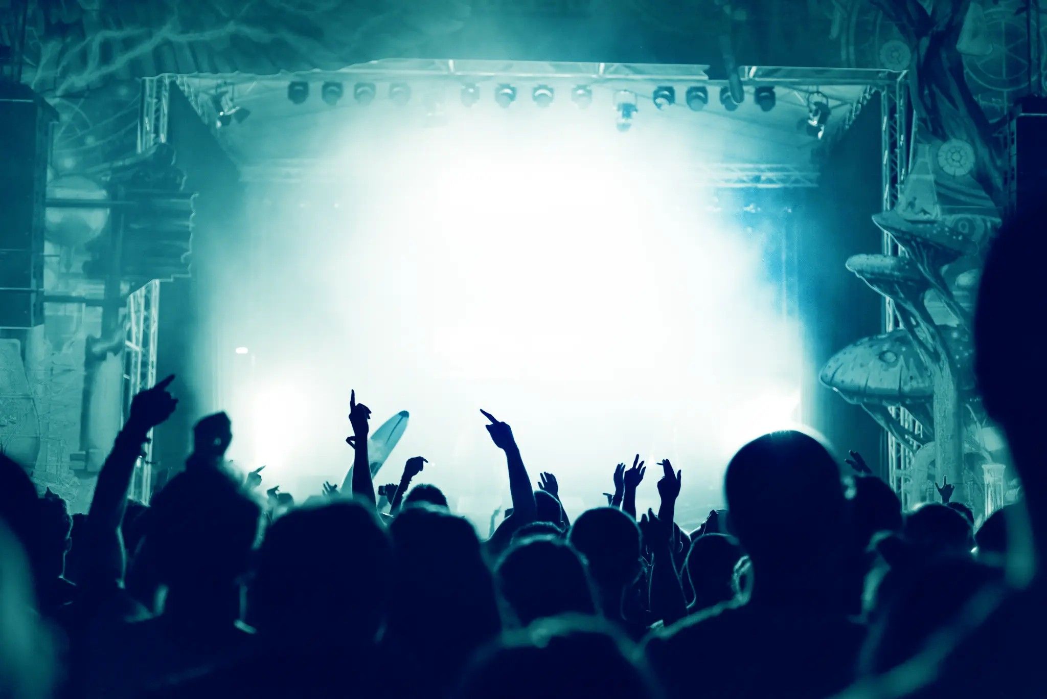 Concert crowd with hands raised under blue stage lights
